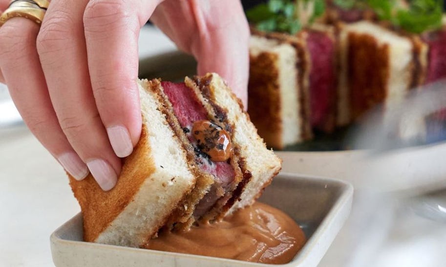 A close up shot of a hand holding a beef sandwich