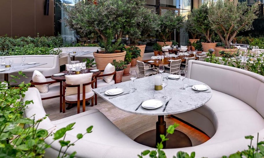 A pretty outdoor terrace packed with sofas and tables in neutral colours