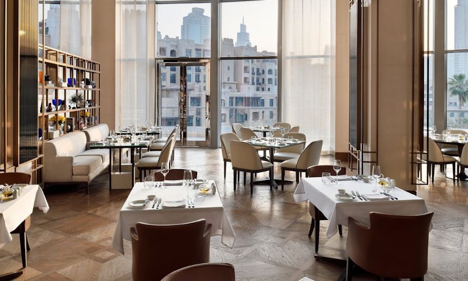 A stylish dining room with floor to ceiling windows and a neutral color scheme 