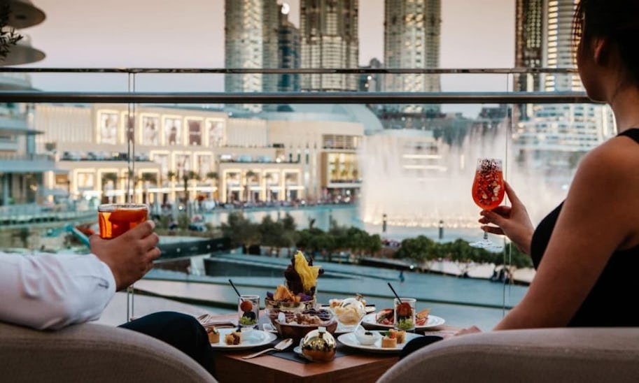 A table with two on a terrace where a couple are enjoying a view of Dubai's fountains as well as a spread of small plates