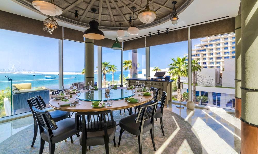 A round private dining table in a room with big windows on two sides looking out to the sw