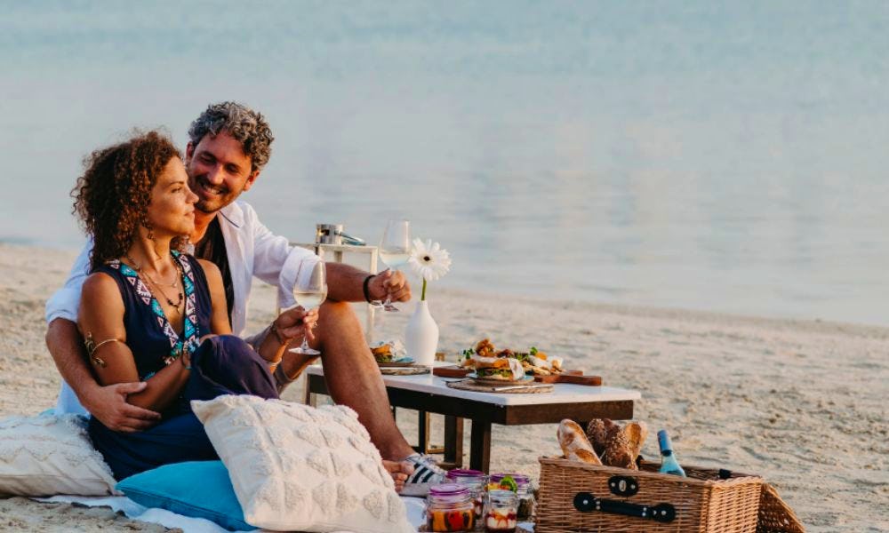 A couple enjoying a picnic on the beach with wine