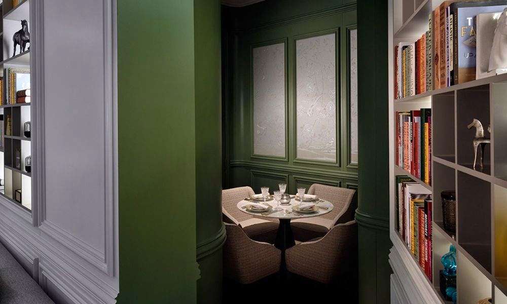 A hidden room behind a door that looks like a bookcase, with a small table inside