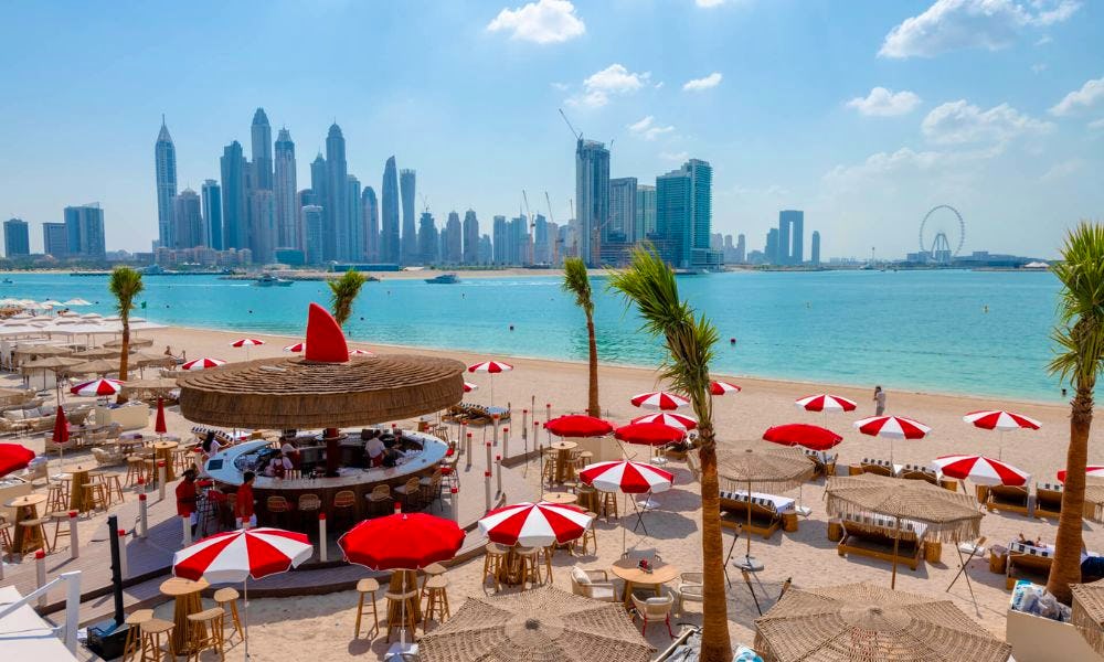 White and red umbrellas and palm trees with Dubai Skyline in background